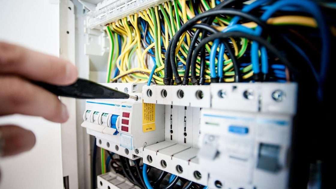 Electrical contractor working on a distribution board with tools, equipment funded through asset finance