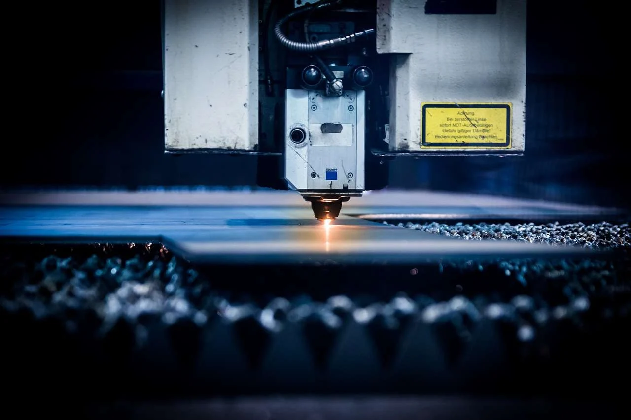 CNC laser cutting machine cutting sheet steel in a UK engineering workshop