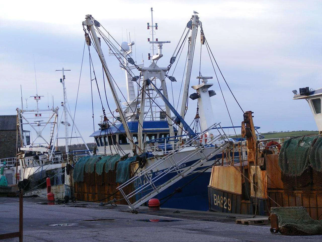 Commercial fishing trawlers moored in harbour with nets on deck
