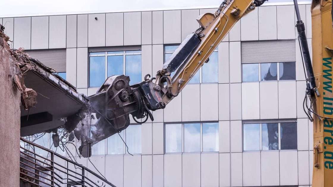 Demolition excavator with a hydraulic shear taking down an office building