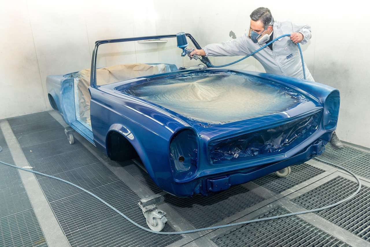 Painter spraying a car in a body shop spray booth