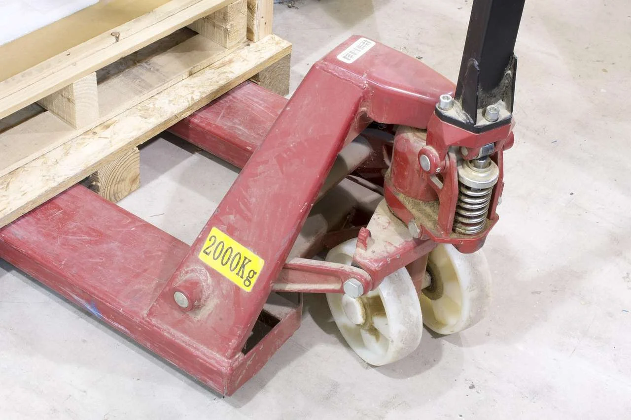 Pallet truck and stacked pallets in a storage warehouse