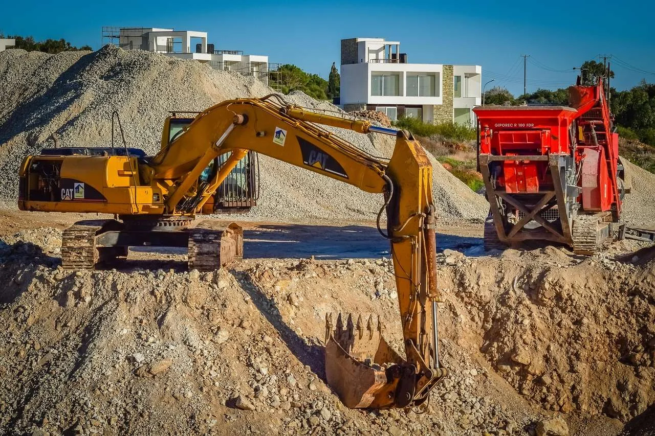 Excavator loading stone beside a crusher in a quarry, equipment funded on hire purchase