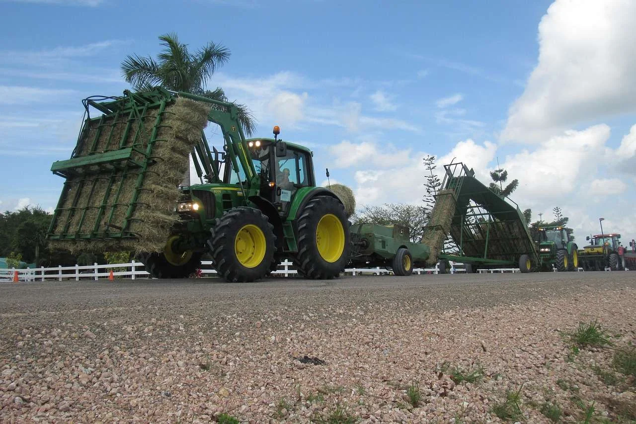 Tractor with a loader moving round bales on a farm, a typical machine bought on hire purchase