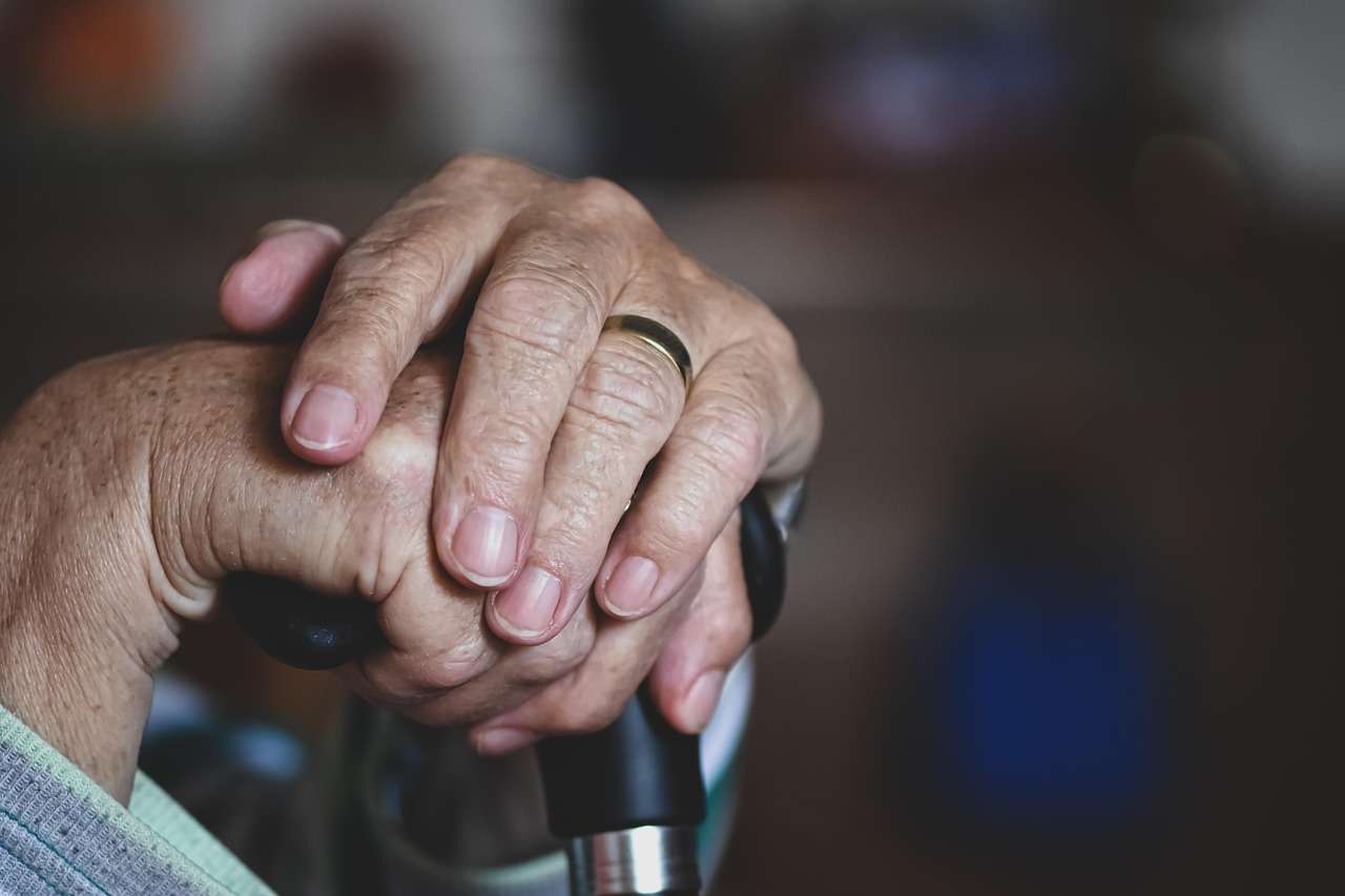 Carer holding the hands of an elderly care home resident