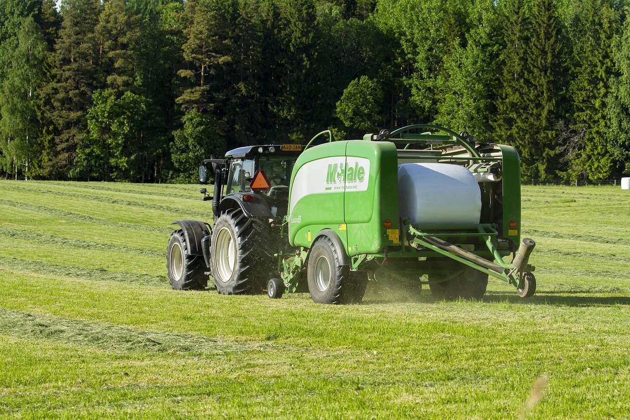 Tractor and round baler working a hay field, farm machinery funded through tractor and farm machinery finance