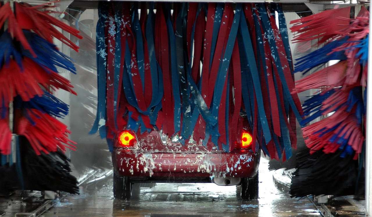 Car passing through an automatic car wash with rotating brushes