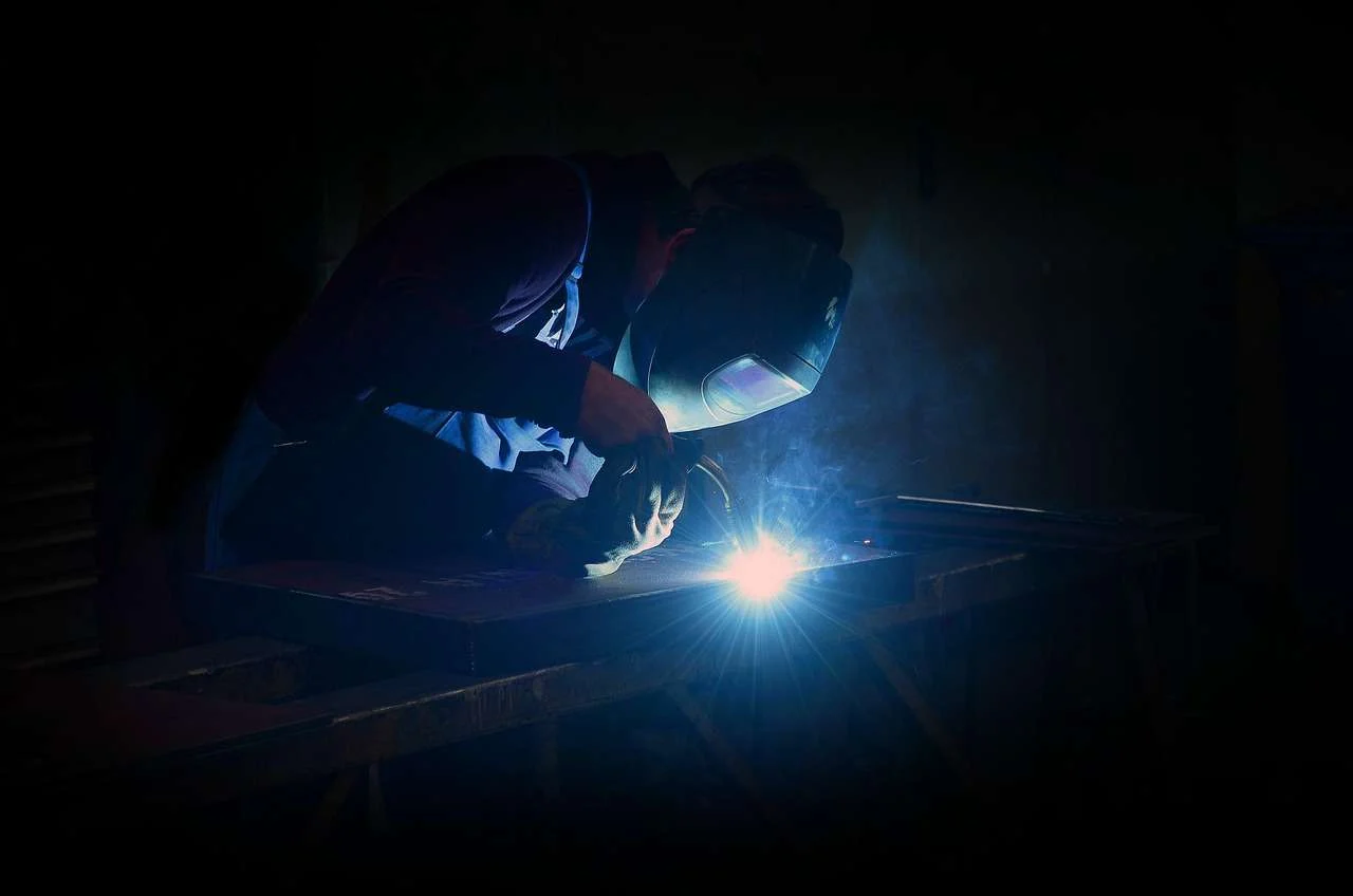Welder in a protective mask with sparks from a MIG weld