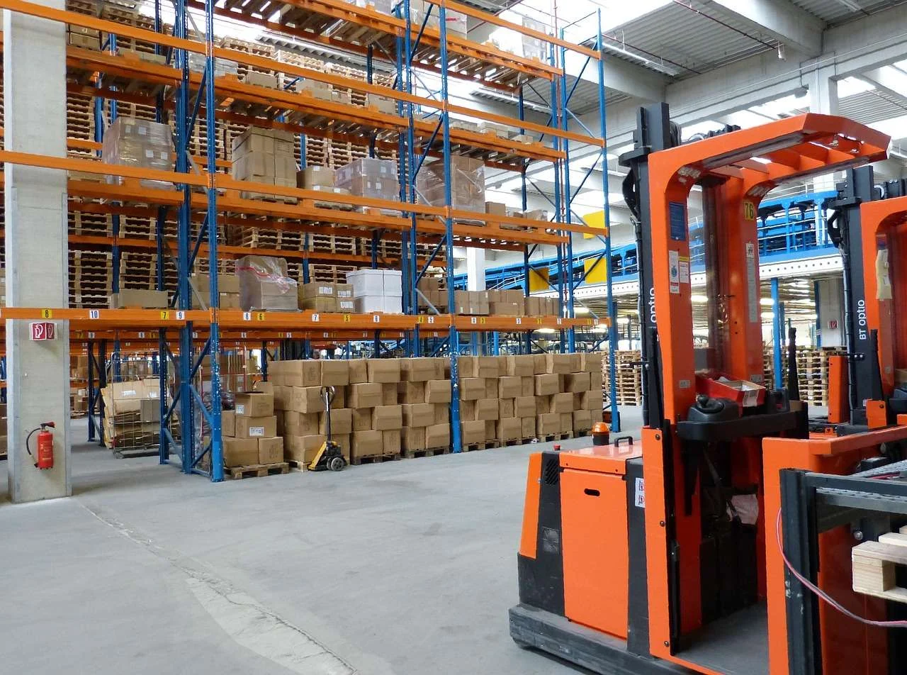 Forklift working between racking in a factory warehouse