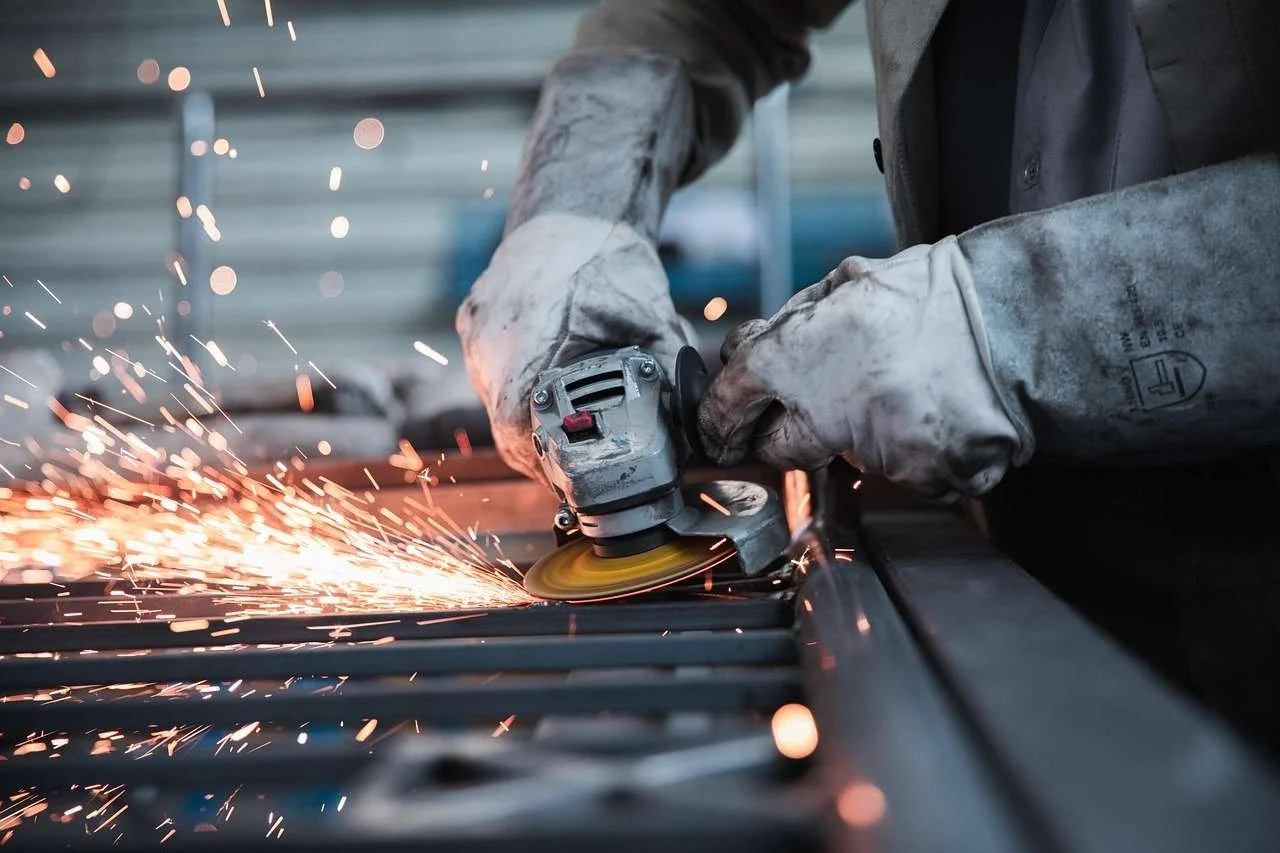 Machinist grinding a steel component in a factory